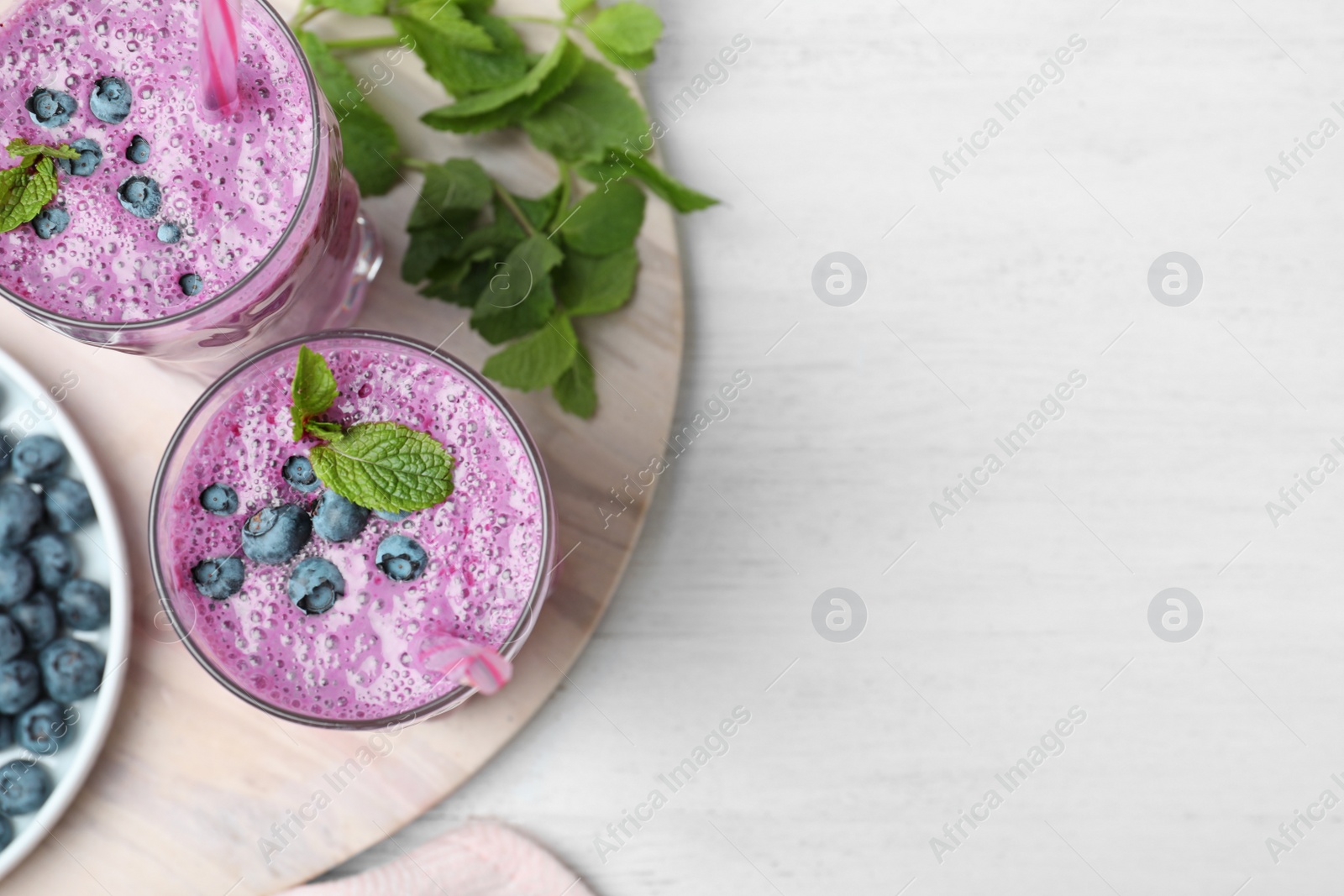 Photo of Marble board with tasty blueberry smoothie on white wooden table, flat lay. Space for text