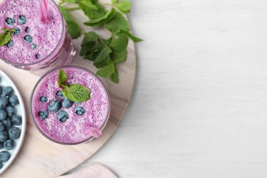 Photo of Marble board with tasty blueberry smoothie on white wooden table, flat lay. Space for text