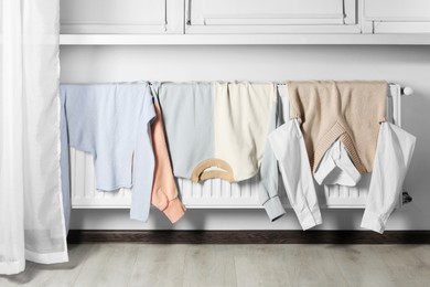Clean clothes hanging on white radiator in room