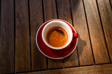 Photo of Cup of aromatic hot coffee on wooden table, above view