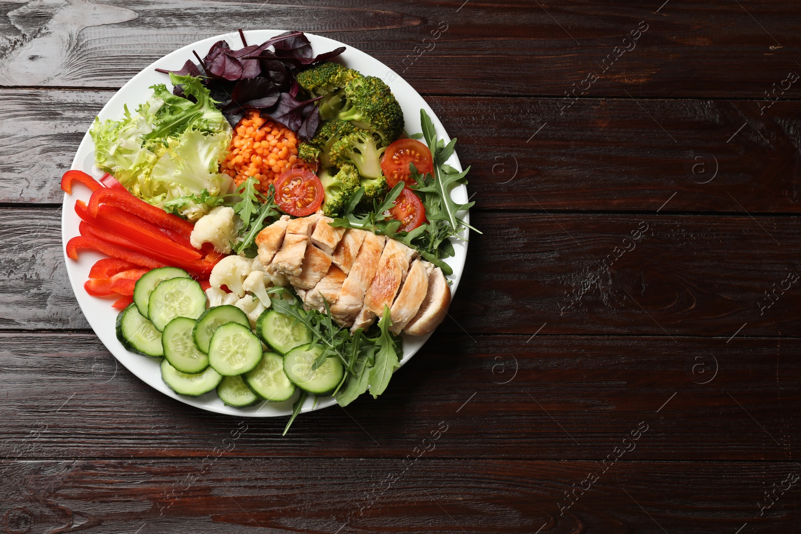 Photo of Balanced diet and healthy foods. Plate with different delicious products on wooden table, top view. Space for text