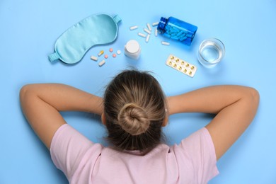Photo of Woman surrounded by different pills on turquoise background, top view. Insomnia treatment