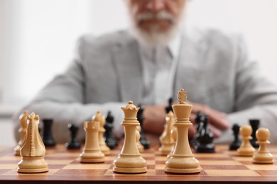 Photo of Chess pieces on chessboard, selective focus. Man participating in tournament indoors