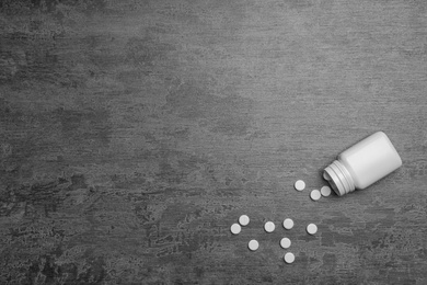 Photo of Container with white pills on grey background