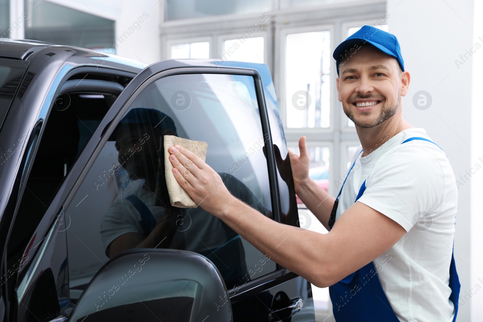 Photo of Worker tinting car window with foil in workshop