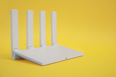 Photo of Modern Wi-Fi router on yellow background. Space for text