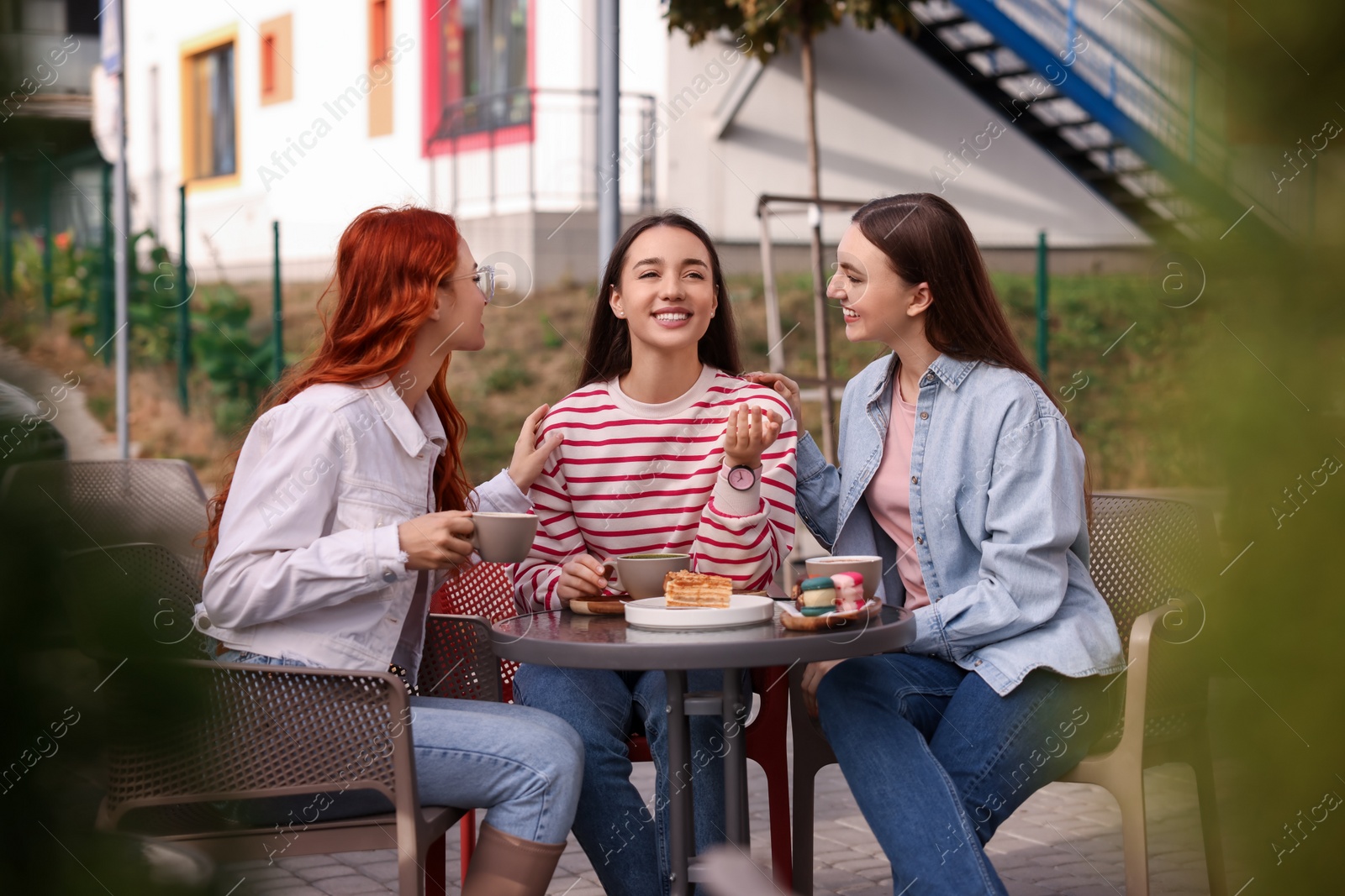 Photo of Happy friends talking and drinking coffee in outdoor cafe