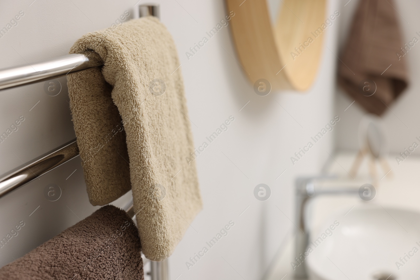 Photo of Heated towel rail with brown towels in bathroom, closeup