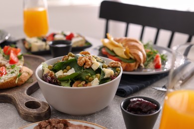 Photo of Bowl of delicious salad and many different dishes served on buffet table for brunch