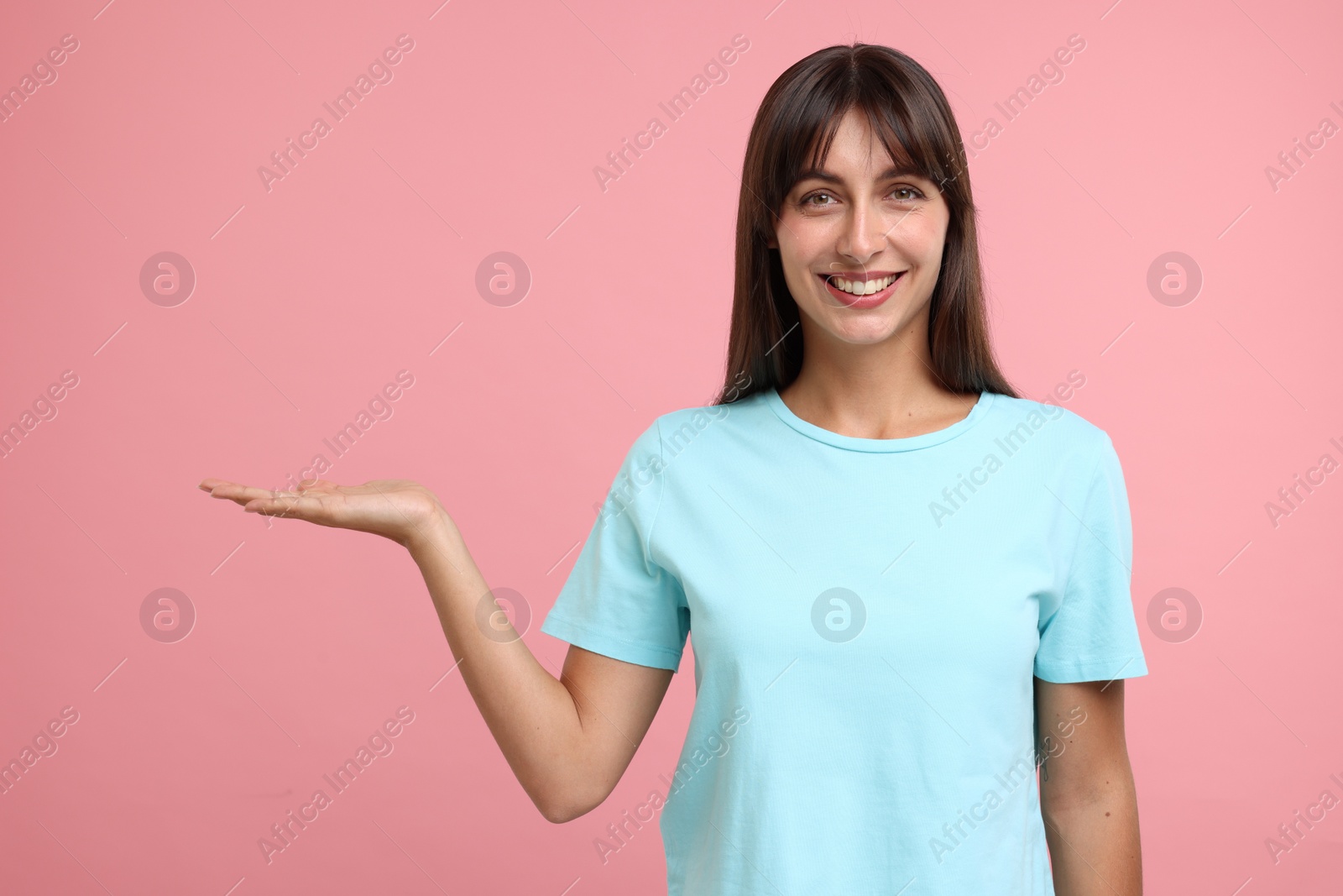 Photo of Special promotion. Happy woman showing something on pink background, space for text