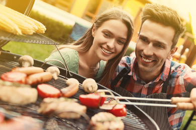 Young man and woman near barbecue grill outdoors on sunny day