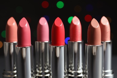 Photo of Different lipsticks against blurred lights. Cosmetic product