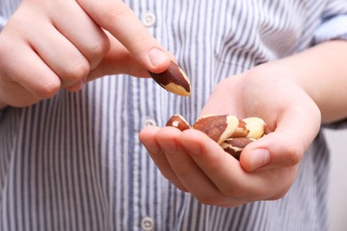 Photo of Woman with tasty Brazil nuts, closeup view