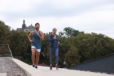 Healthy lifestyle. Happy sporty couple running outdoors, space for text