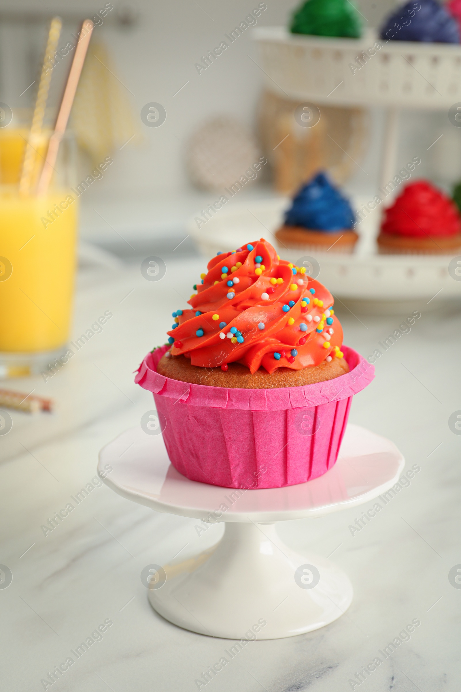 Photo of Delicious cupcake with bright cream and sprinkles on white table