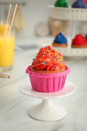 Delicious cupcake with bright cream and sprinkles on white table