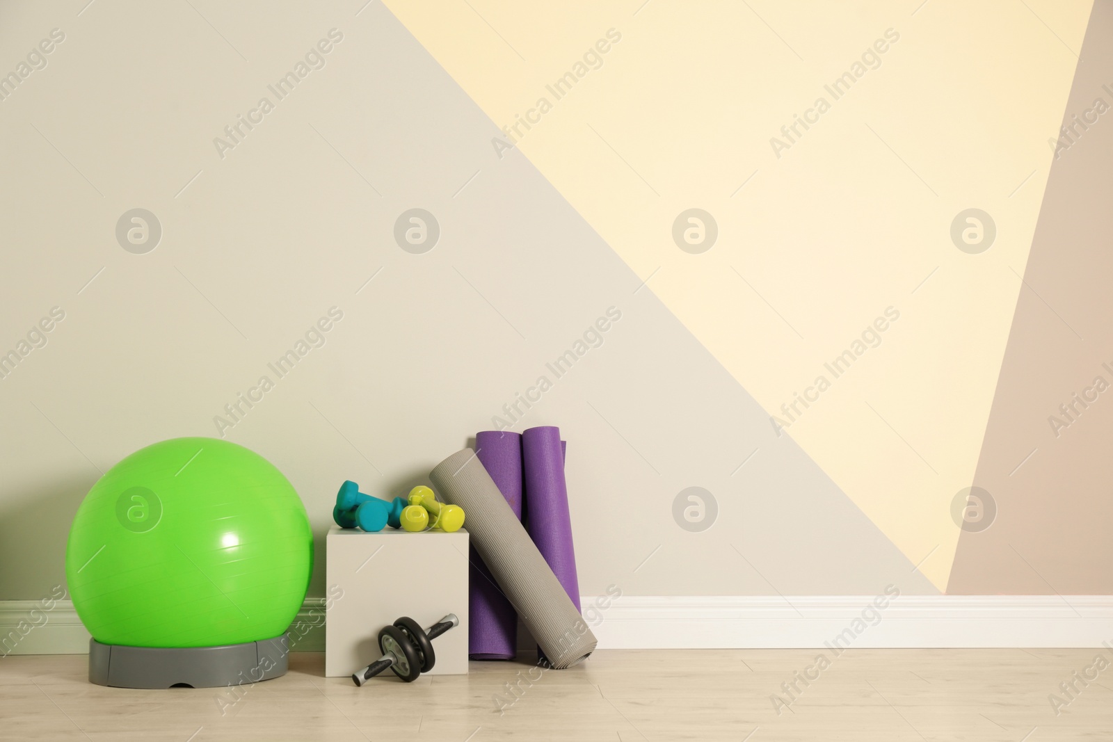 Photo of Set of fitness inventory on floor near color wall, space for text. Rehabilitation medicine