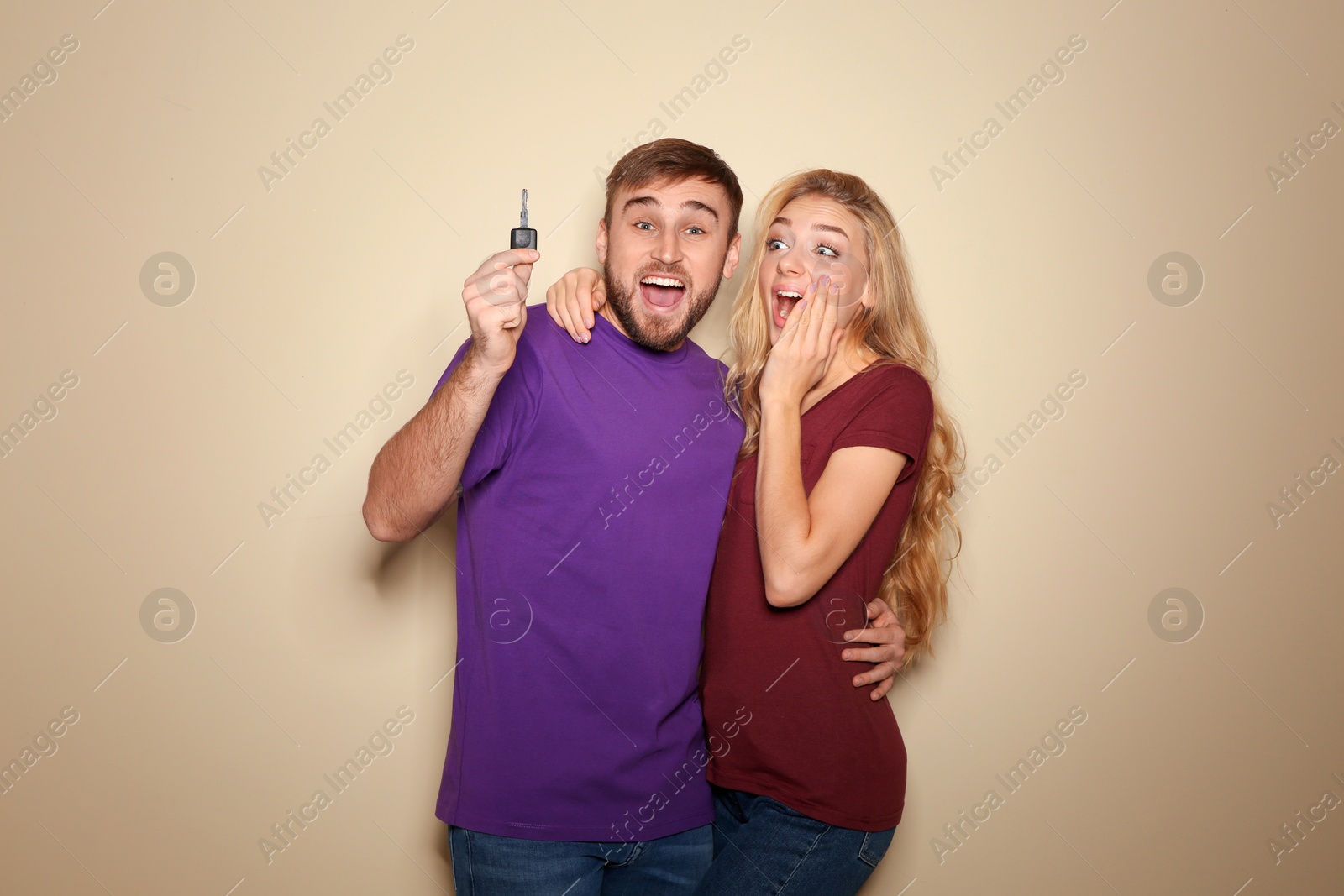 Photo of Happy young couple with car key on color background