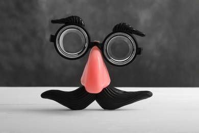 Funny face made with clown's accessories on white wooden table