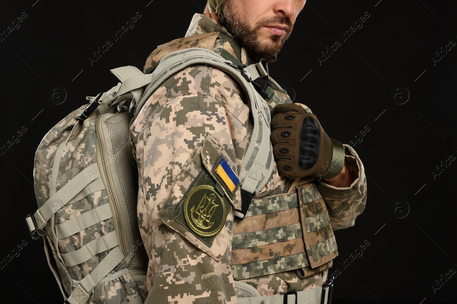 Photo of Soldier in Ukrainian military uniform with backpack on black background, closeup