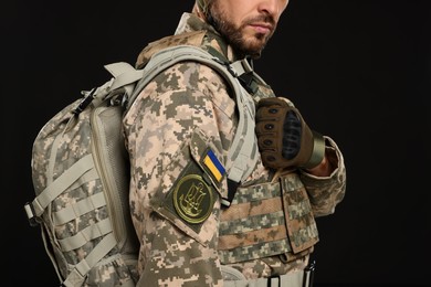 Photo of Soldier in Ukrainian military uniform with backpack on black background, closeup