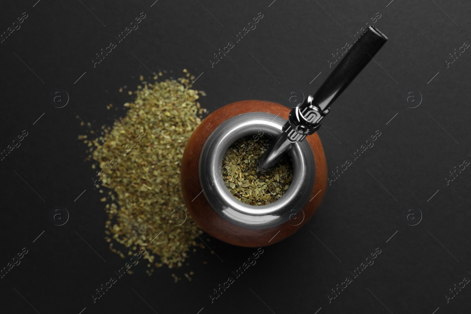 Photo of Calabash with mate tea and bombilla on black table, flat lay