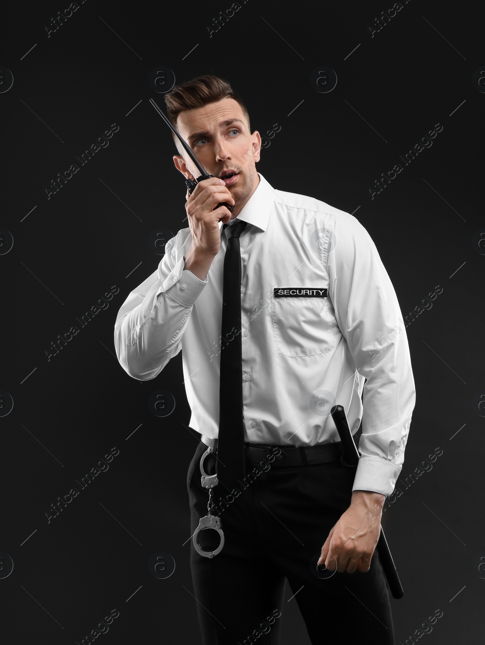 Photo of Male security guard using portable radio transmitter on dark background