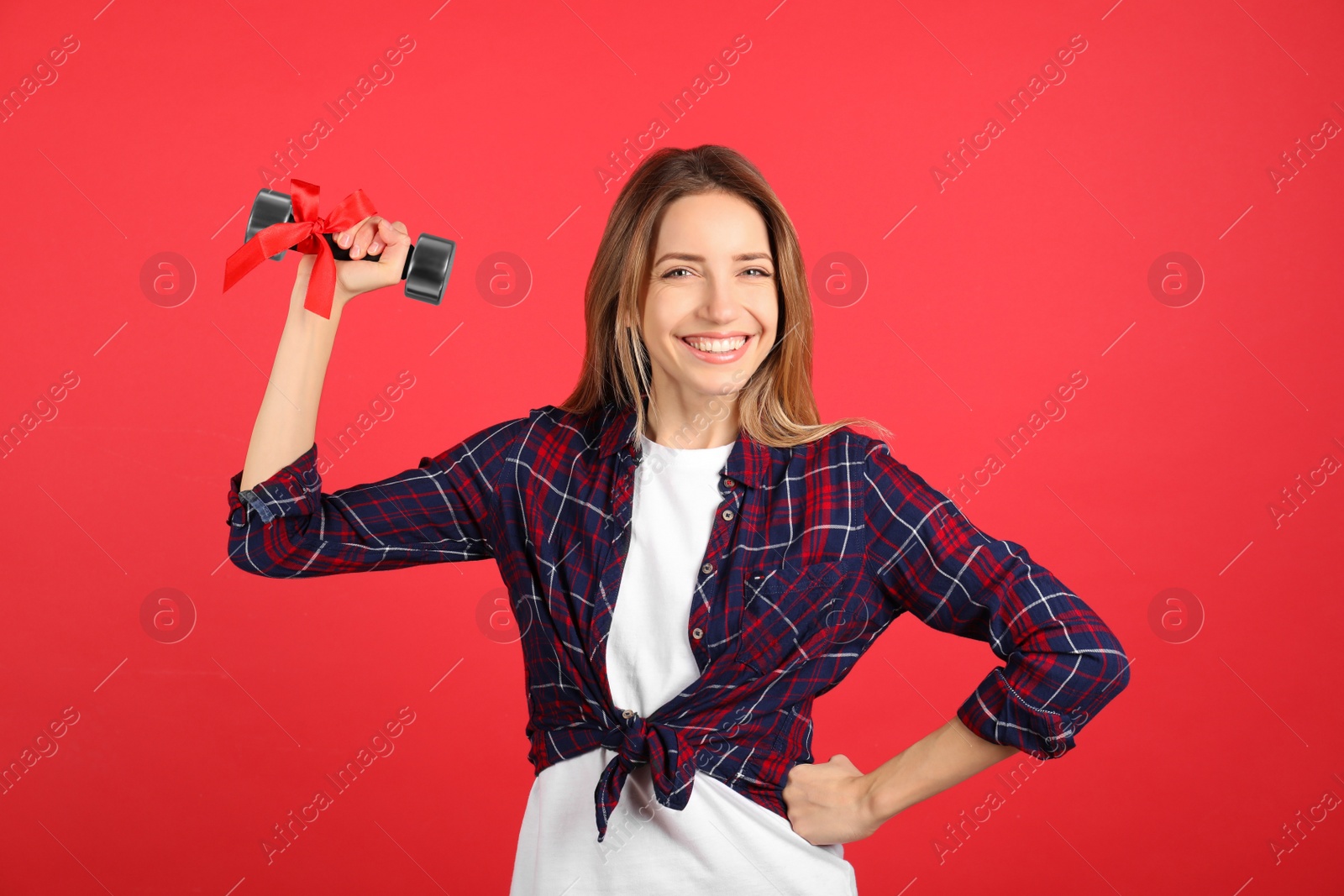 Photo of Woman with dumbbell as symbol of girl power on red background. 8 March concept