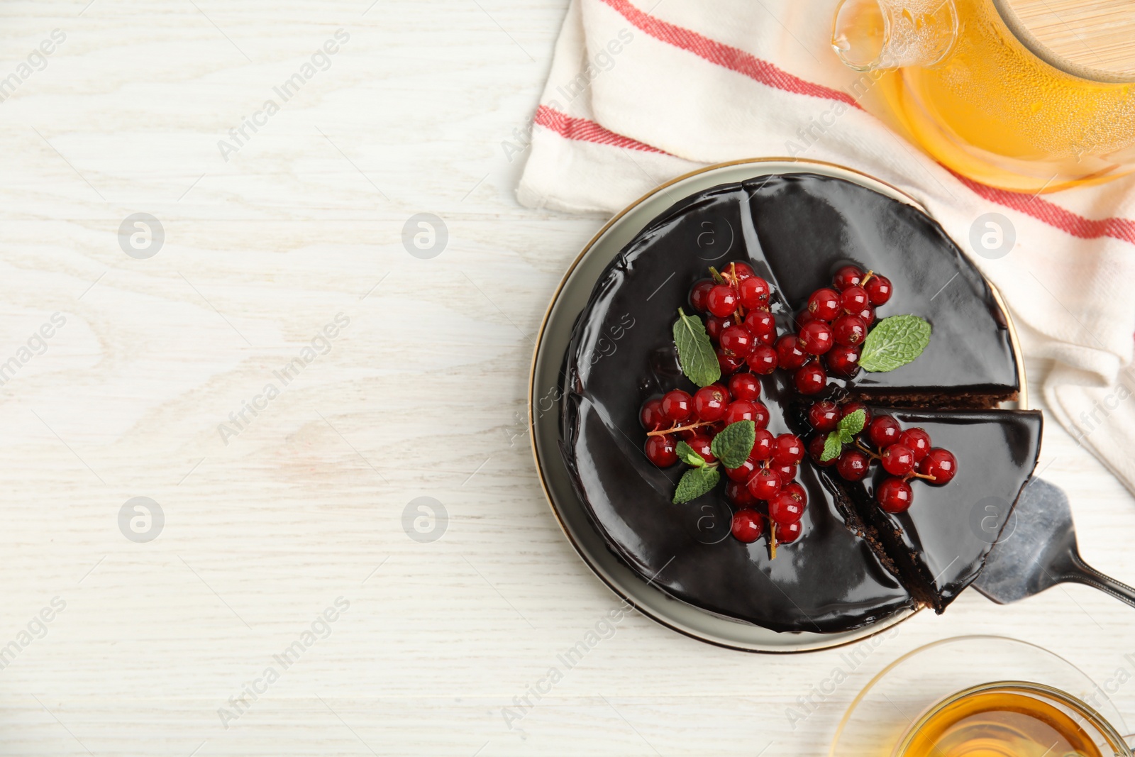 Photo of Tasty homemade chocolate cake served with berries, mint and tea on white wooden table, flat lay. Space for text