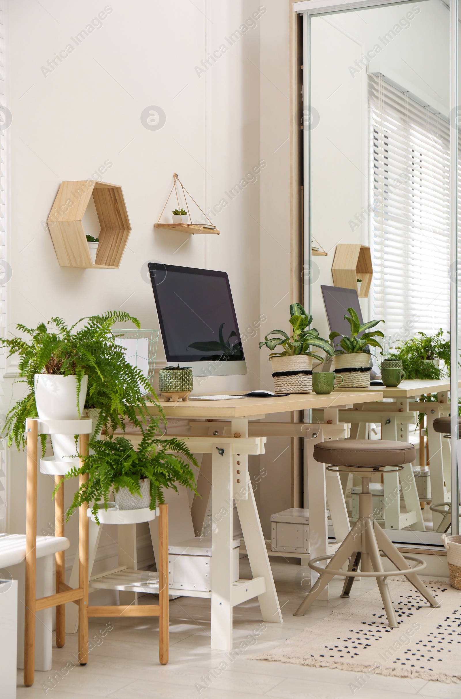 Photo of Comfortable workplace with modern computer and houseplants in room. Interior design