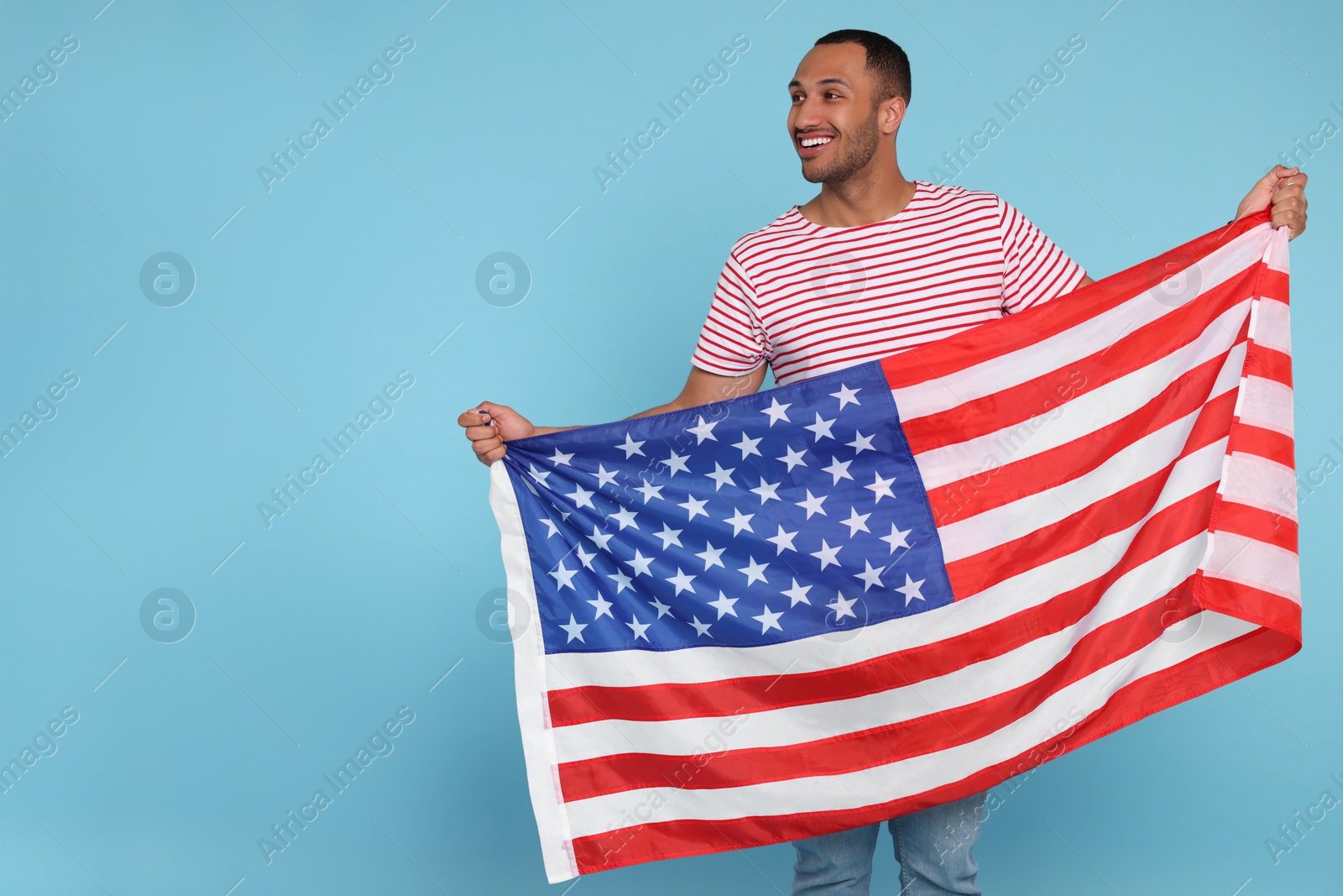 Photo of 4th of July - Independence Day of USA. Happy man with American flag on light blue background, space for text