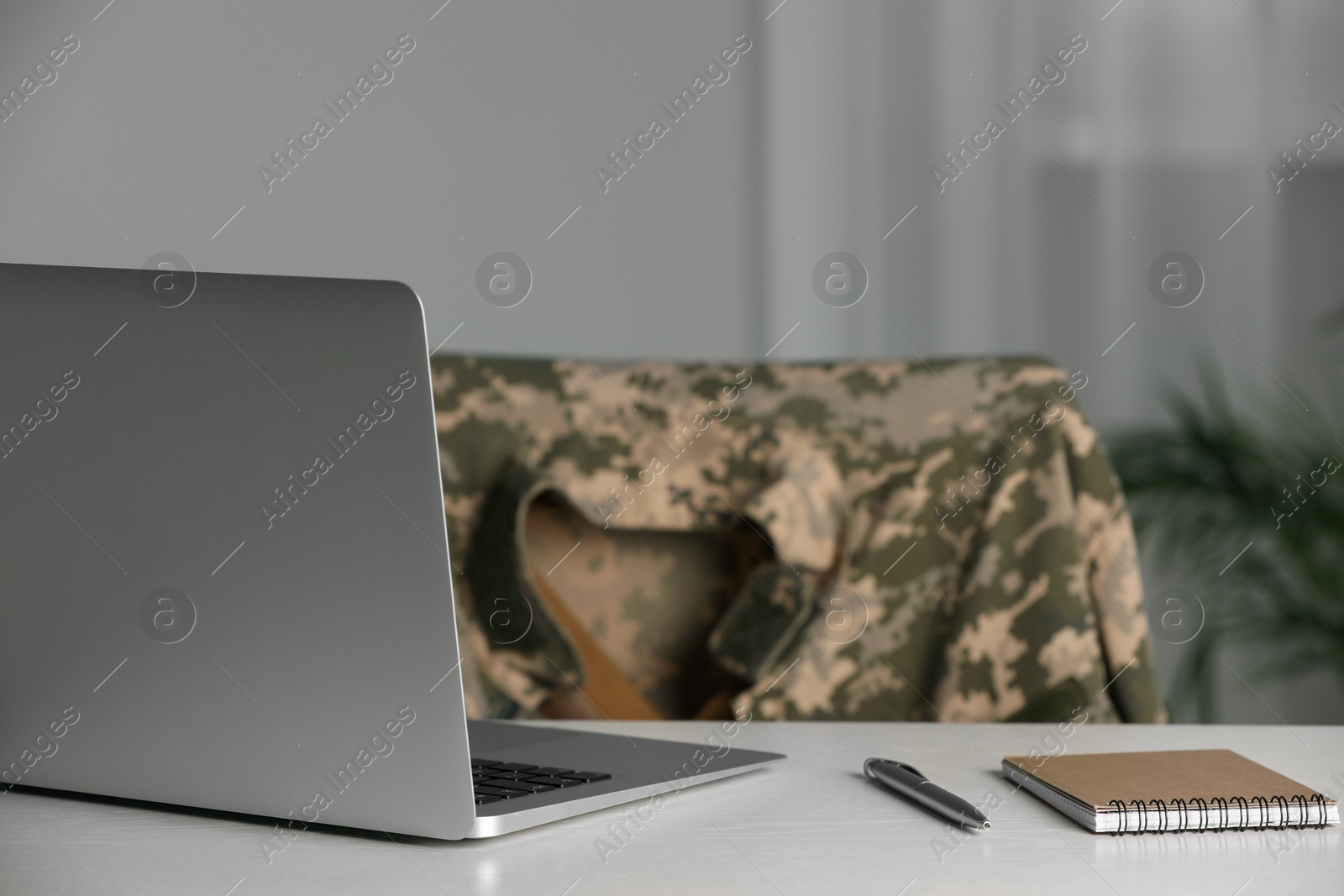 Photo of Notebook, laptop and pen on white table indoors. Military education