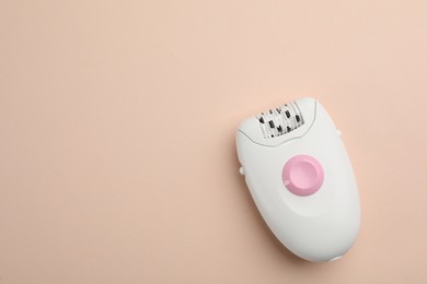 Modern epilator on beige background, top view. Space for text