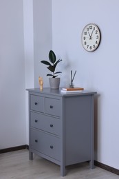 Chest of drawers with decor elements near white wall in room. Interior design