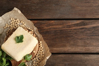 Photo of Piece of delicious tofu with parsley and soy on wooden table, top view. Space for text