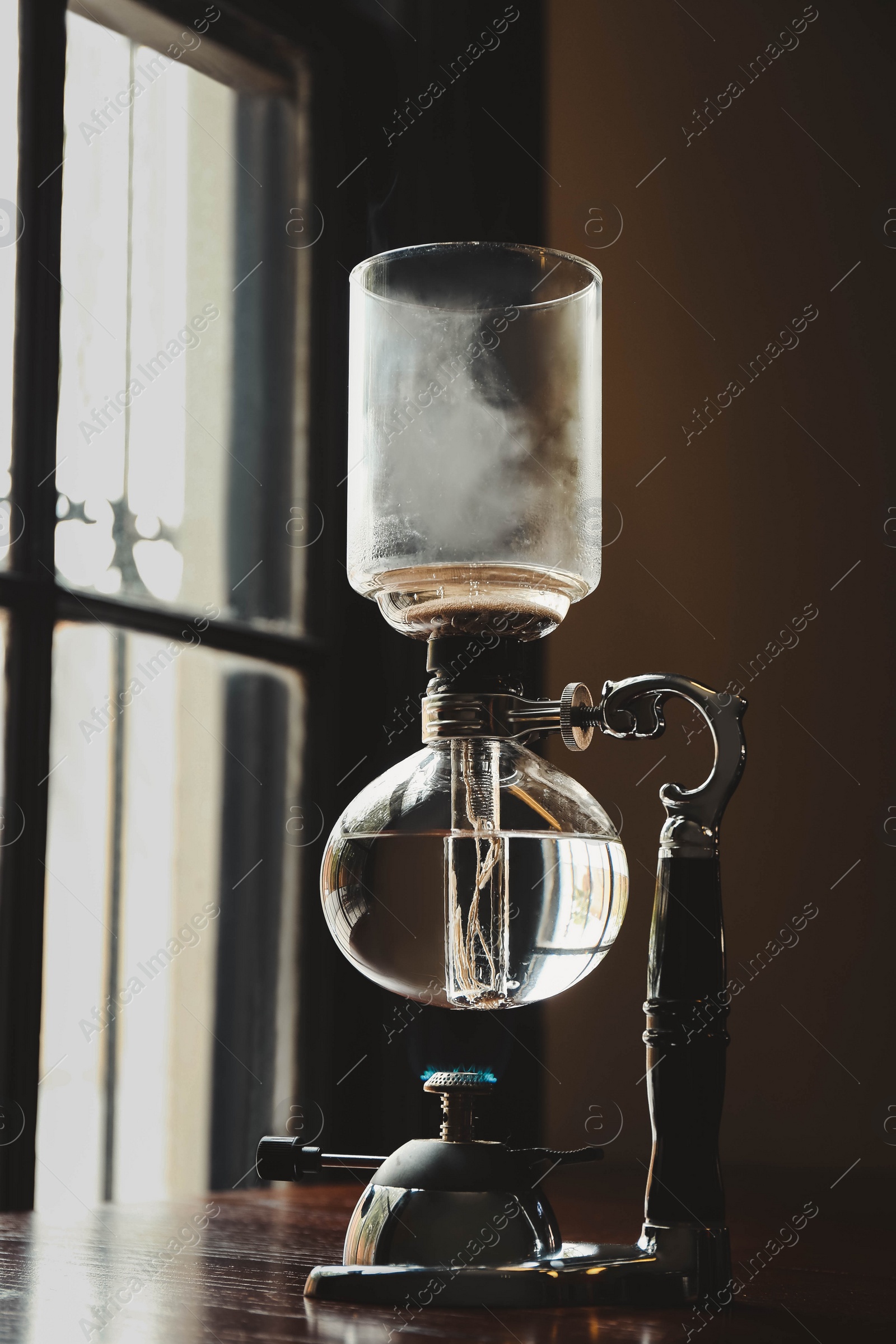 Photo of Vacuum coffee maker on wooden table in cafe