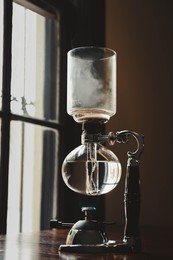 Photo of Vacuum coffee maker on wooden table in cafe