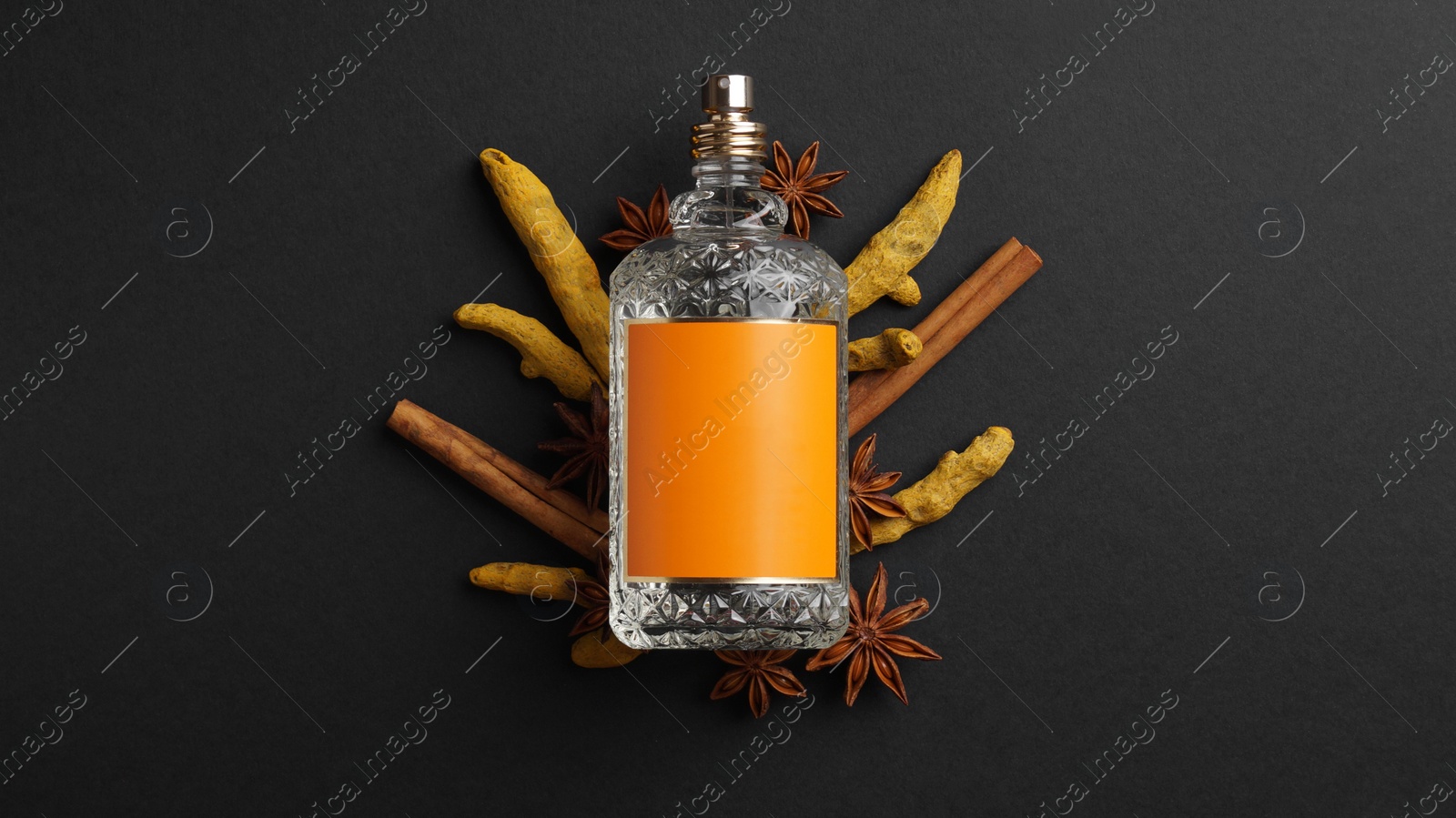 Photo of Bottle of perfume surrounded by different spices on dark background, top view