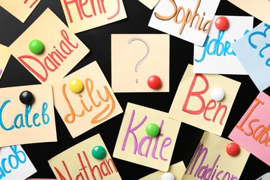 Photo of Notes with baby names on black board, closeup