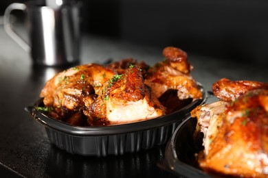 Cooked pieces of grilled chicken in plastic containers on bar counter, closeup. Food delivery service