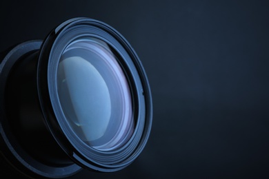 Photo of Lens of professional camera on dark blue background, closeup. Space for text