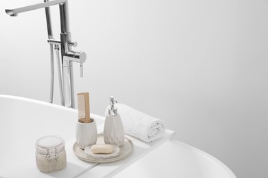 Different personal care products and accessories on bath tub in bathroom, space for text