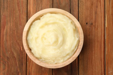 Photo of Bowl of tasty mashed potato on wooden table, top view