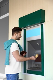 Photo of Young man with credit card near cash machine outdoors