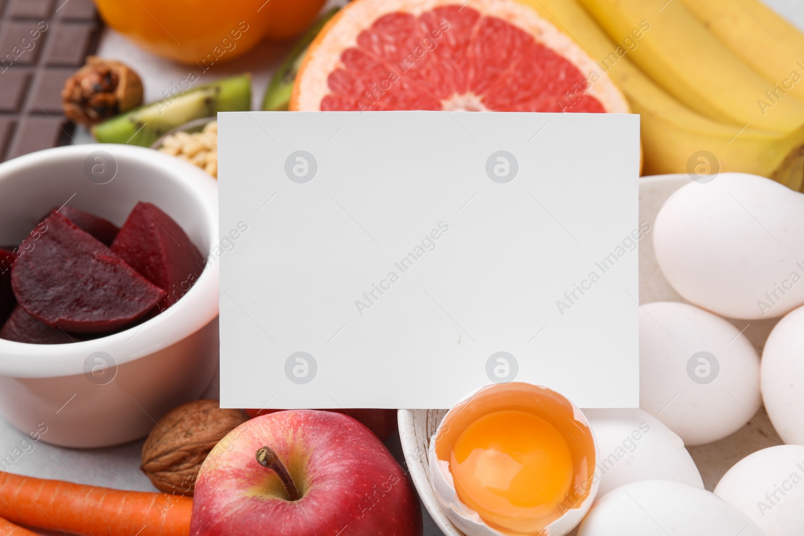 Photo of Many different products and blank card on table, closeup. Natural sources of serotonin