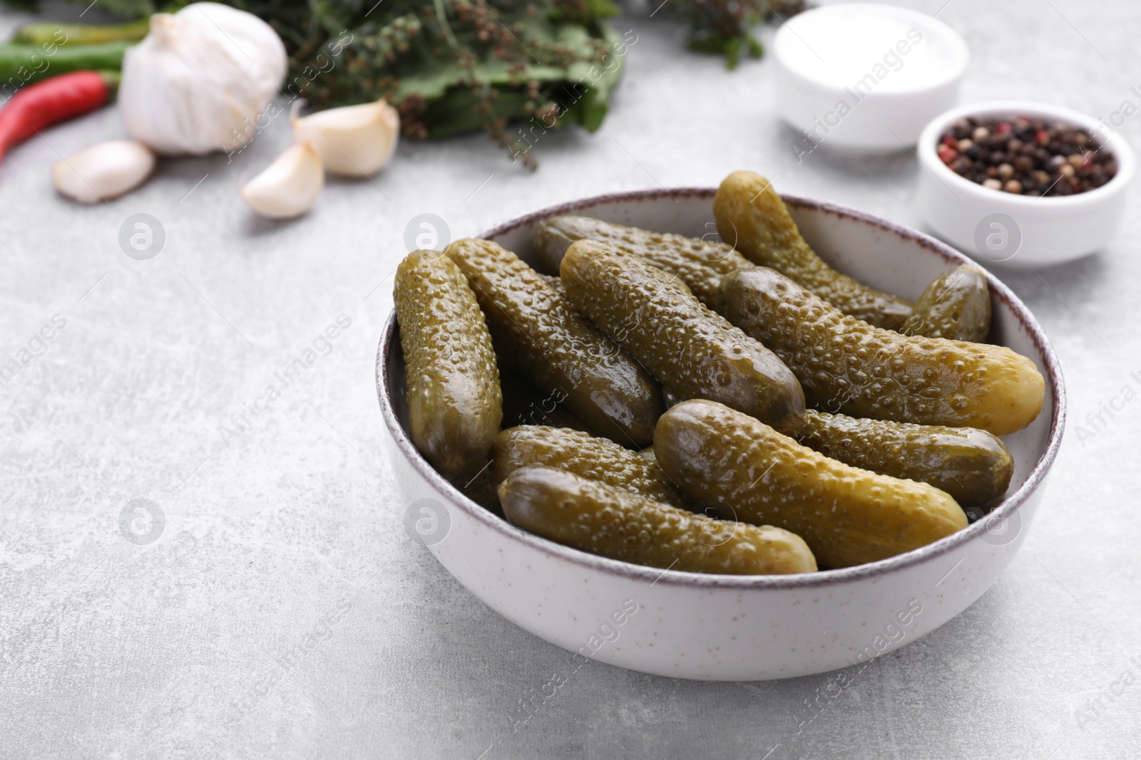 Photo of Pickled cucumbers and ingredients on light grey table