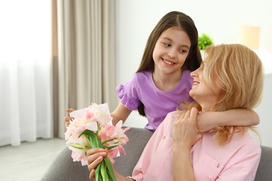 Photo of Little daughter congratulating her mature mom at home, space for text. Happy Mother's Day