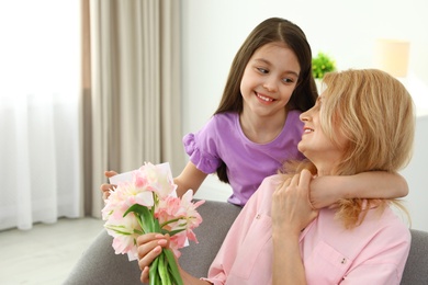 Little daughter congratulating her mature mom at home, space for text. Happy Mother's Day