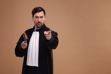 Photo of Judge in court dress with gavel on light brown background. Space for text