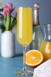 Photo of Glass of Mimosa cocktail on light blue wooden table